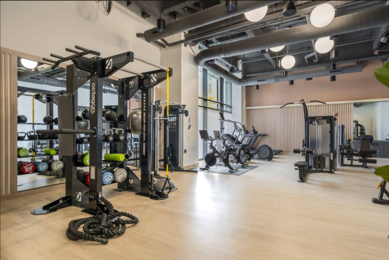 Spacious, well-lit gym equipped with a variety of cardio machines, free weights, and strength-training equipment.