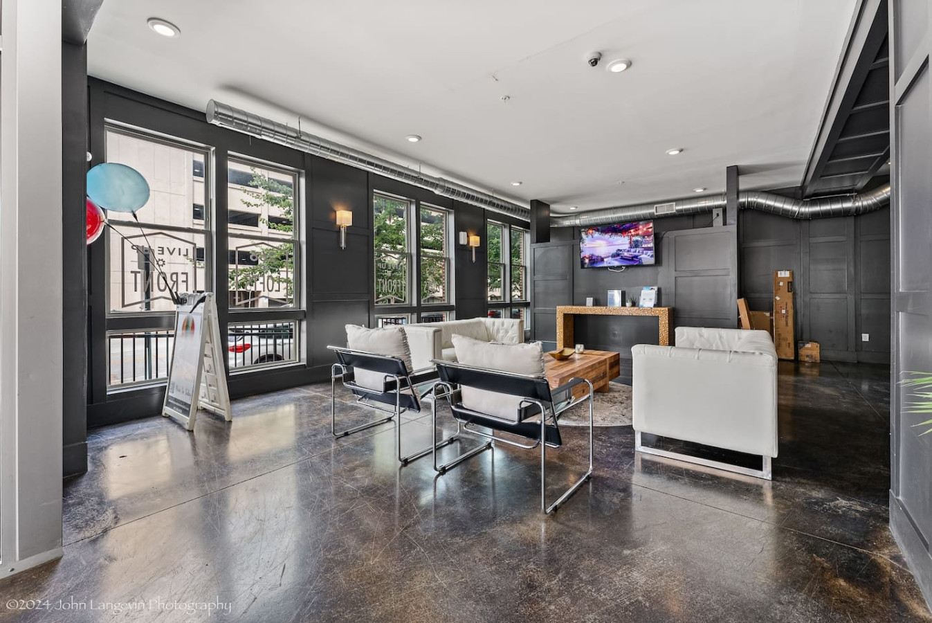 Enjoy a stylish and welcoming living space featuring modern decor and a large flat-screen TV. The unique mirror reflects the vibrant "Good Vibes Only" sign, adding a playful touch to the ambiance. Perfect for relaxation and entertainment.
