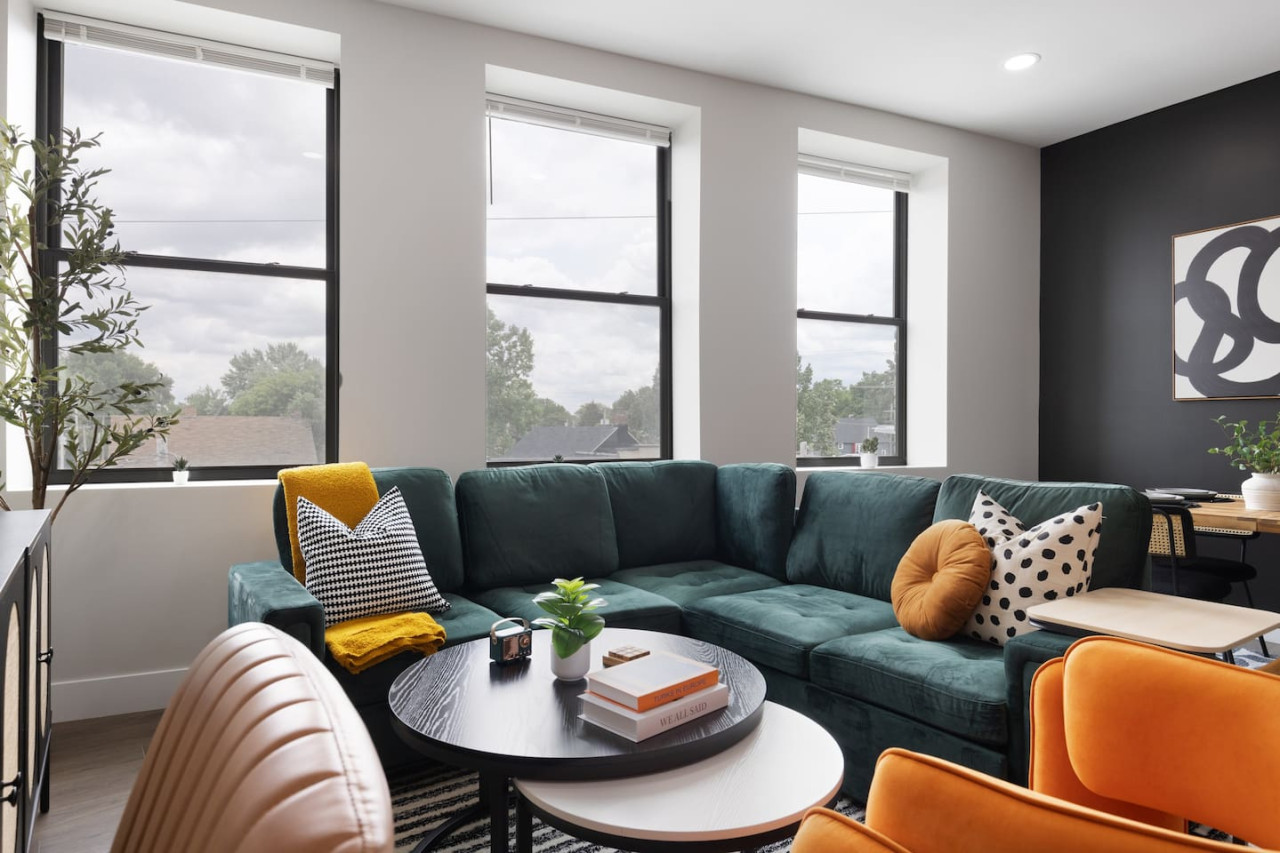 Enjoy a blend of modern comfort and style in this spacious living area. Featuring a plush sofa, chic decor, and a vibrant neon sign, it's perfect for relaxation and socializing. The open layout seamlessly connects to the kitchen and dining area.