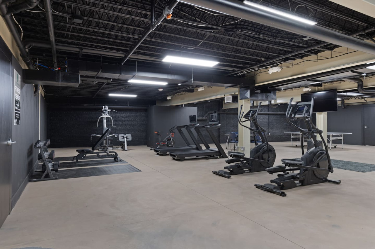 Spacious, well-lit gym equipped with a variety of cardio machines, free weights, and strength-training equipment.