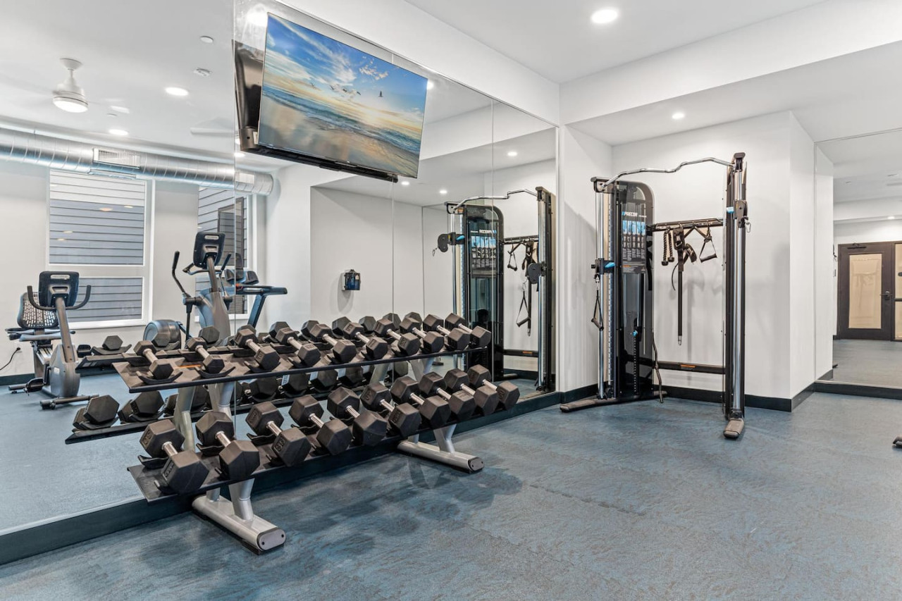 Spacious, well-lit gym equipped with a variety of cardio machines, free weights, and strength-training equipment.