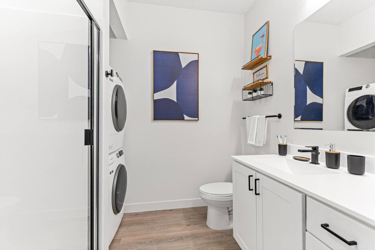 This bright and welcoming bathroom invites you to freshen up in comfort. Enjoy the forest-inspired shower curtain that adds a calming touch to your routine, complemented by the cozy rug underfoot and sparkling clean fixtures.