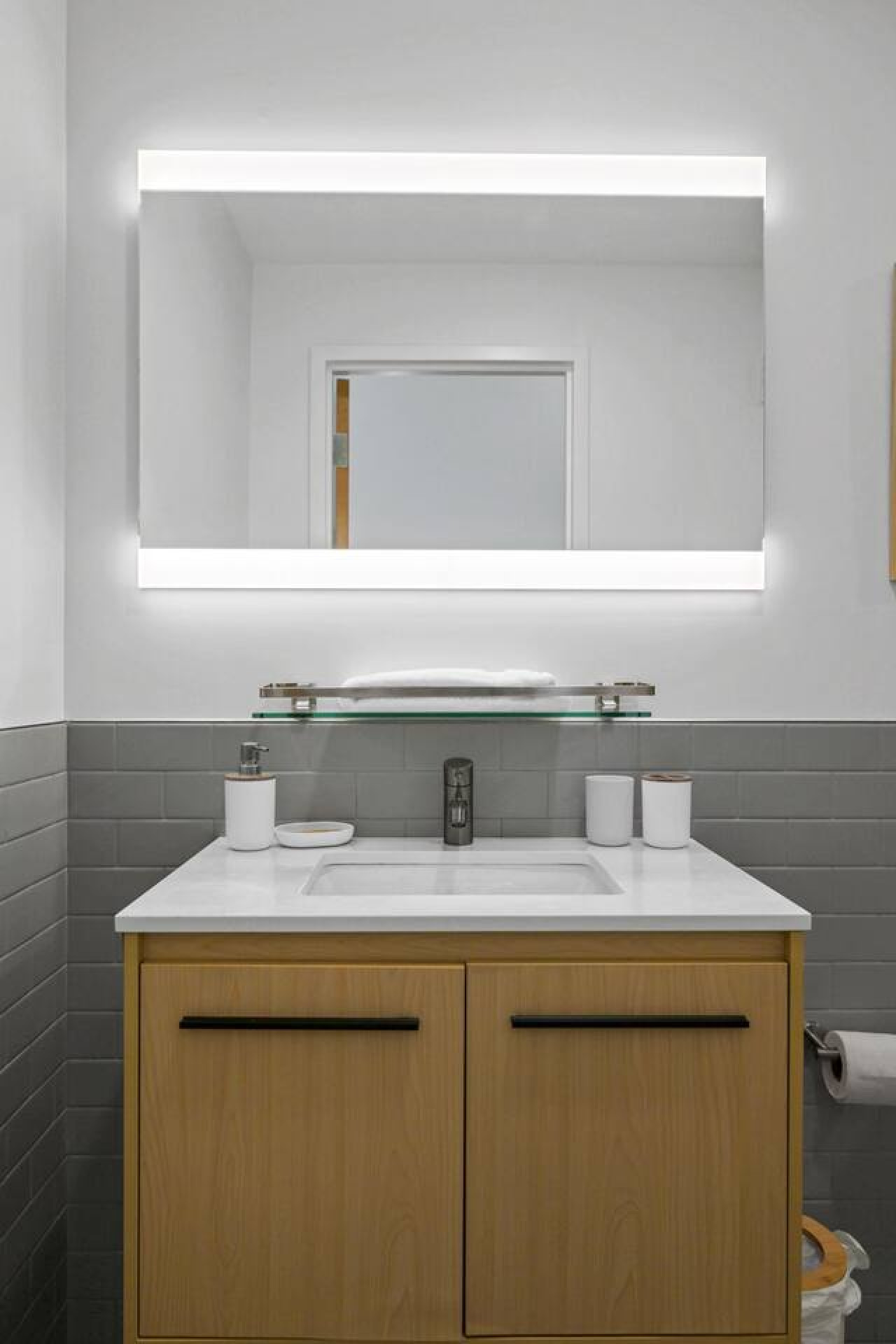 This bright and welcoming bathroom invites you to freshen up in comfort. Enjoy the forest-inspired shower curtain that adds a calming touch to your routine, complemented by the cozy rug underfoot and sparkling clean fixtures.