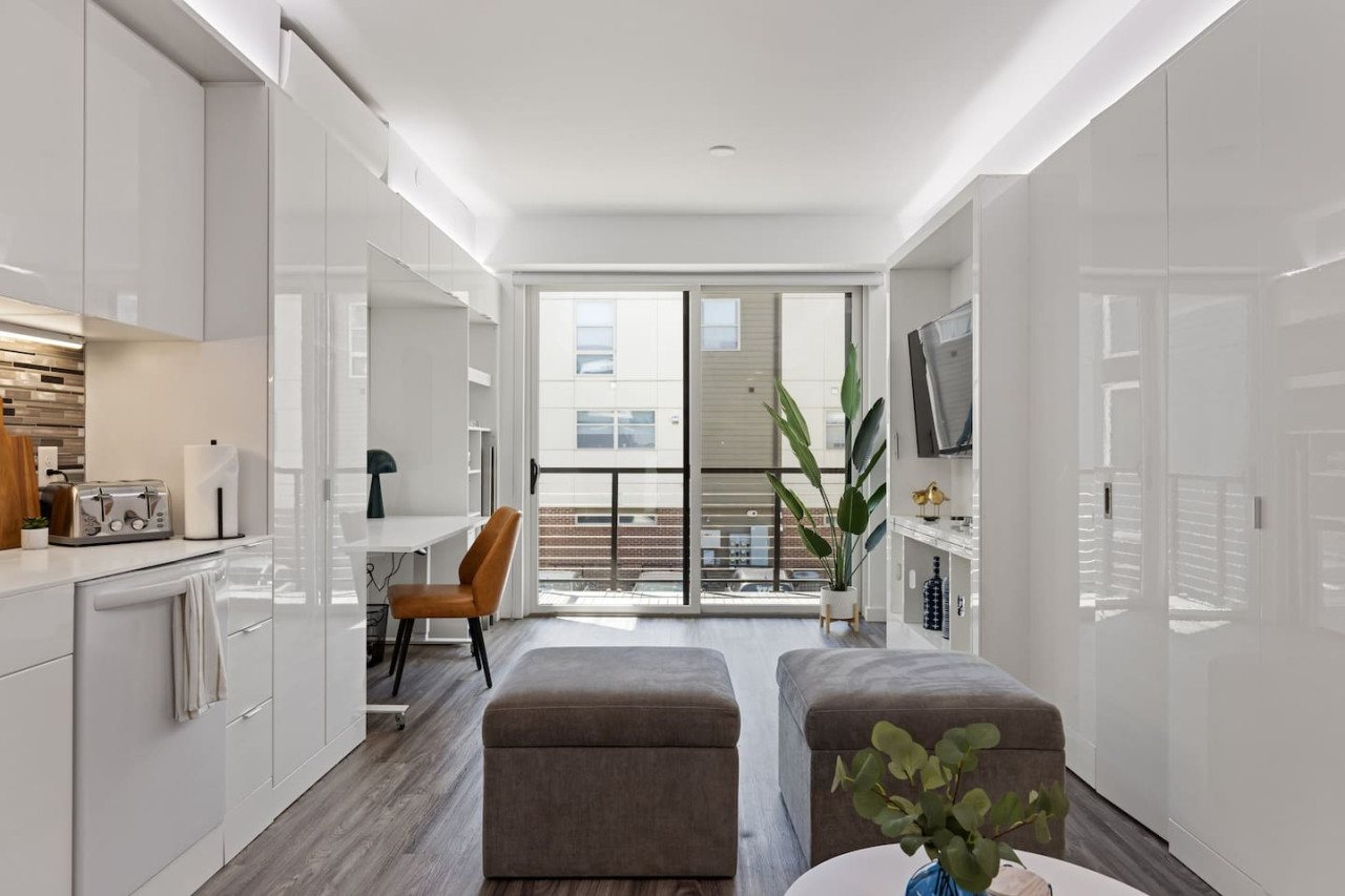 Spacious open-concept living and dining area featuring a vibrant blue sofa, modern furnishings, and a stylish entertainment setup—ideal for gatherings and relaxation.
