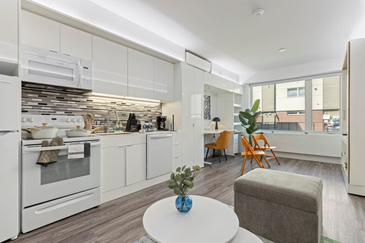Spacious open-concept living and dining area featuring a vibrant blue sofa, modern furnishings, and a stylish entertainment setup—ideal for gatherings and relaxation.