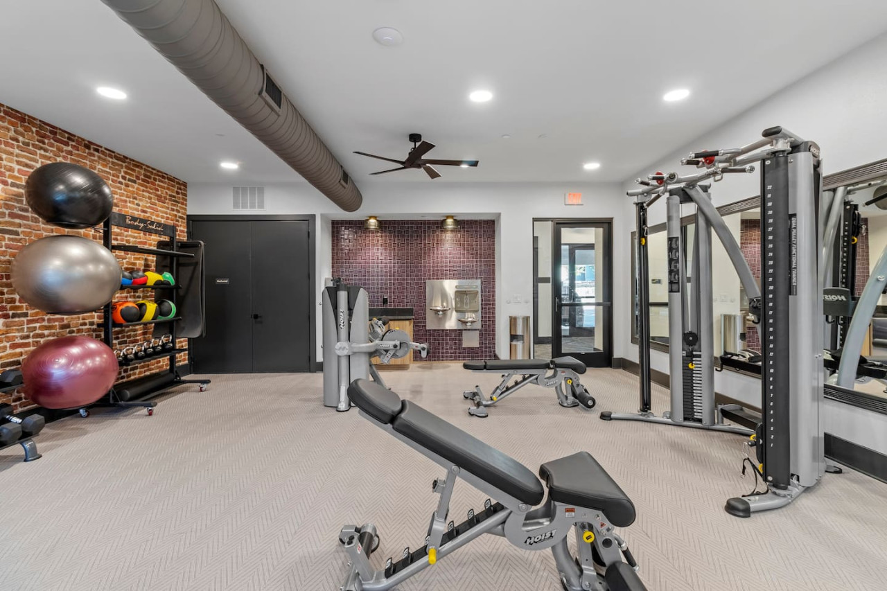 Spacious, well-lit gym equipped with a variety of cardio machines, free weights, and strength-training equipment.