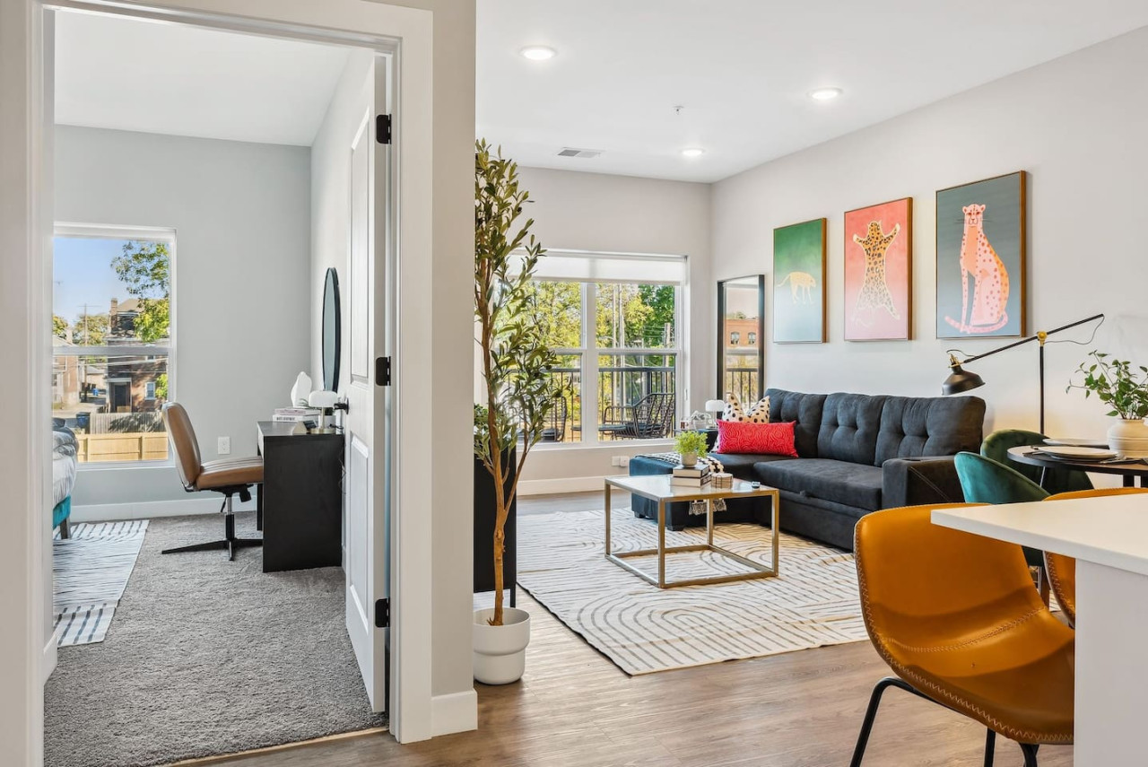 Spacious open-concept living and dining area featuring a vibrant blue sofa, modern furnishings, and a stylish entertainment setup—ideal for gatherings and relaxation.