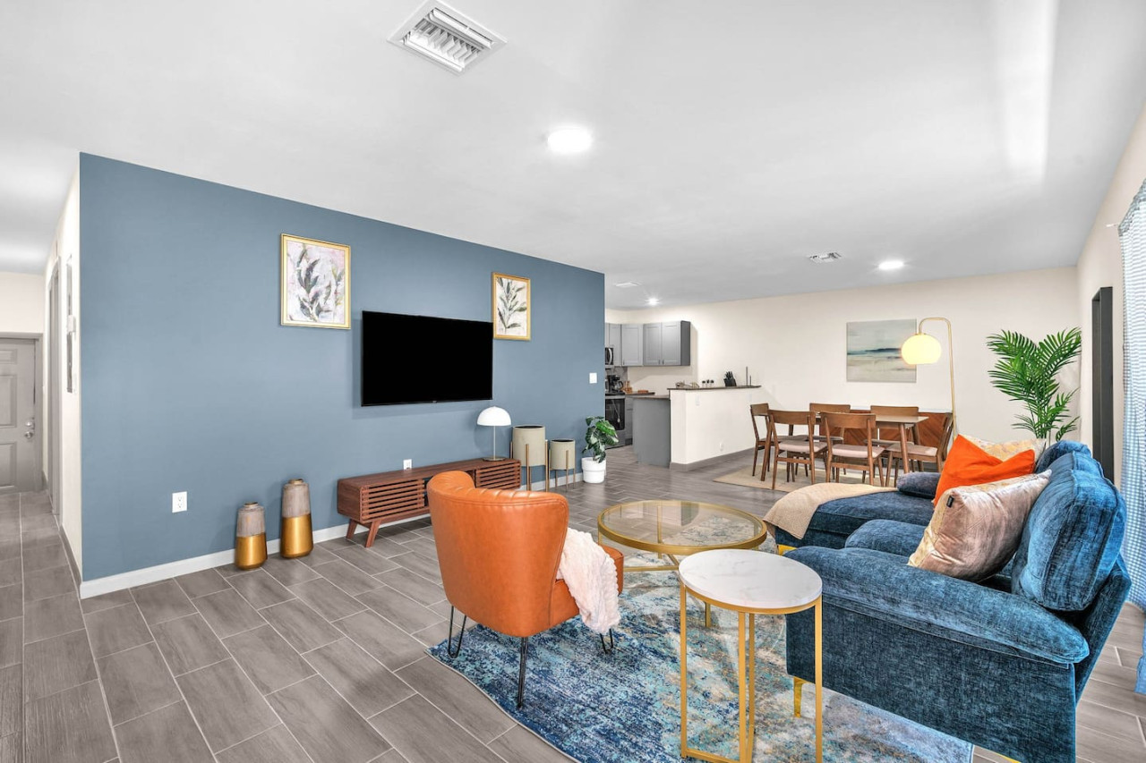Spacious open-concept living and dining area featuring a vibrant sofa, modern furnishings, and a stylish entertainment setup—ideal for gatherings and relaxation.