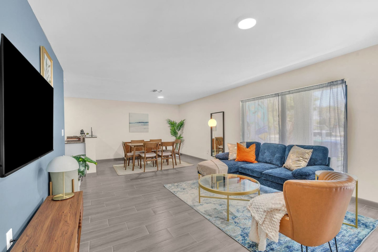 This modern living room features a bold blue and brown color scheme, a cozy sectional, a sleek TV console, stylish decor, warm lighting, and contemporary artwork.