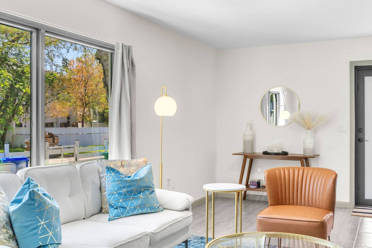 White sofa with a caramel accent chair and glass coffee table.