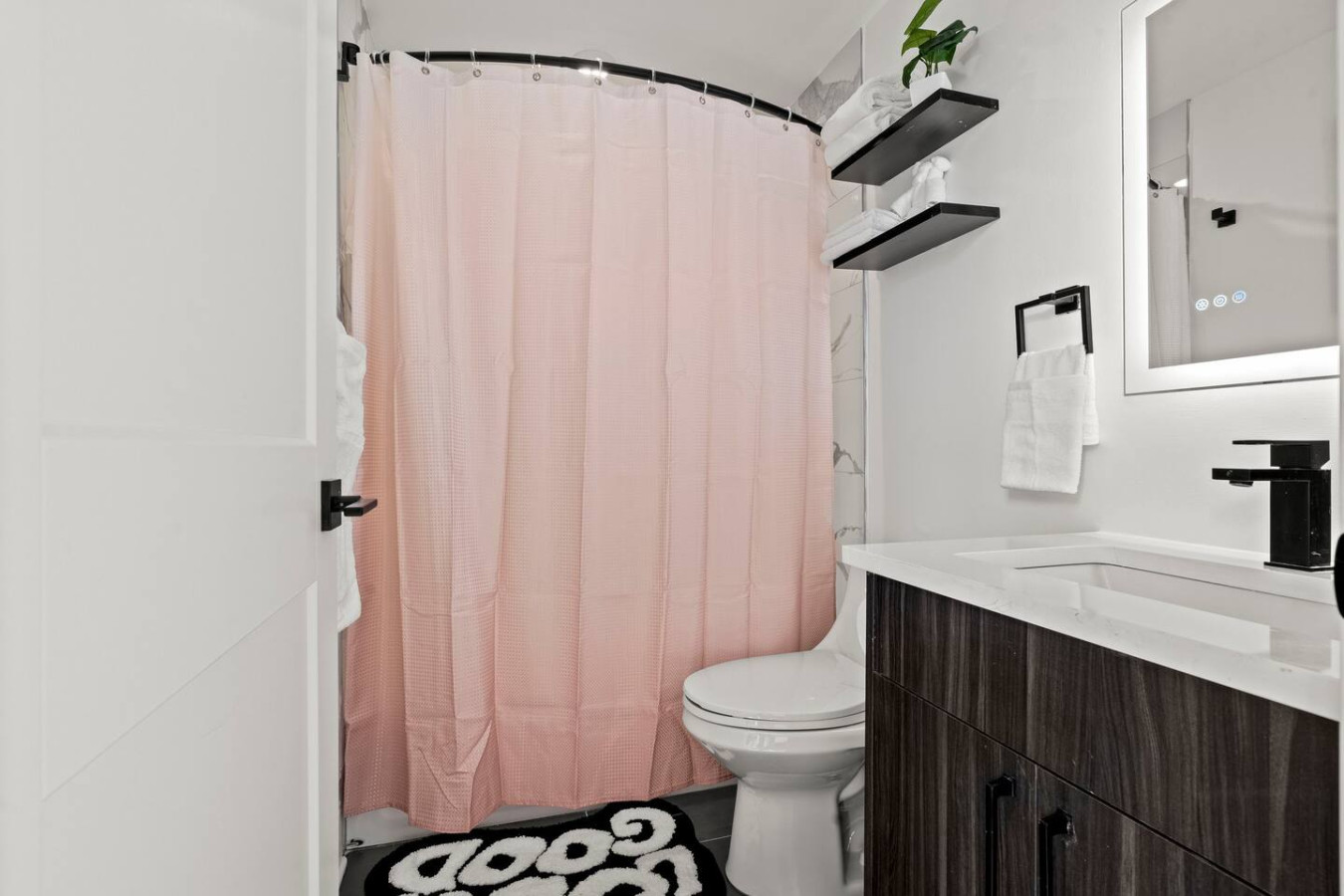 Fully Equipped Bathroom with Single Vanity, Backlit Mirror, and Towels