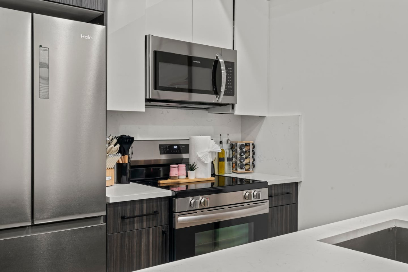 Modern kitchen with stainless steel fridge, stove, microwave, oven, utensils, knifes, spices, and more.
