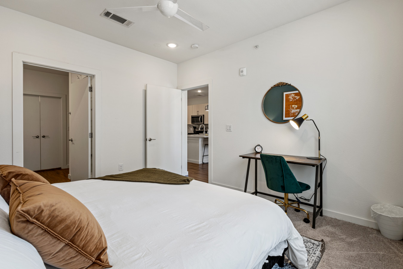 A cozy bedroom featuring a comfortable bed, dedicated workspace, and convenient access to the kitchen.