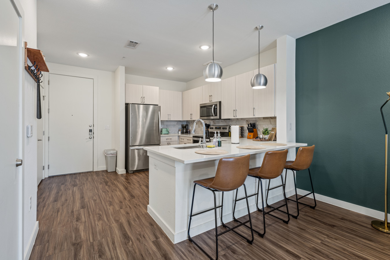 Sleek, modern kitchen featuring white cabinetry, stainless steel appliances, and a spacious island with seating—perfect for gathering and meal prep.