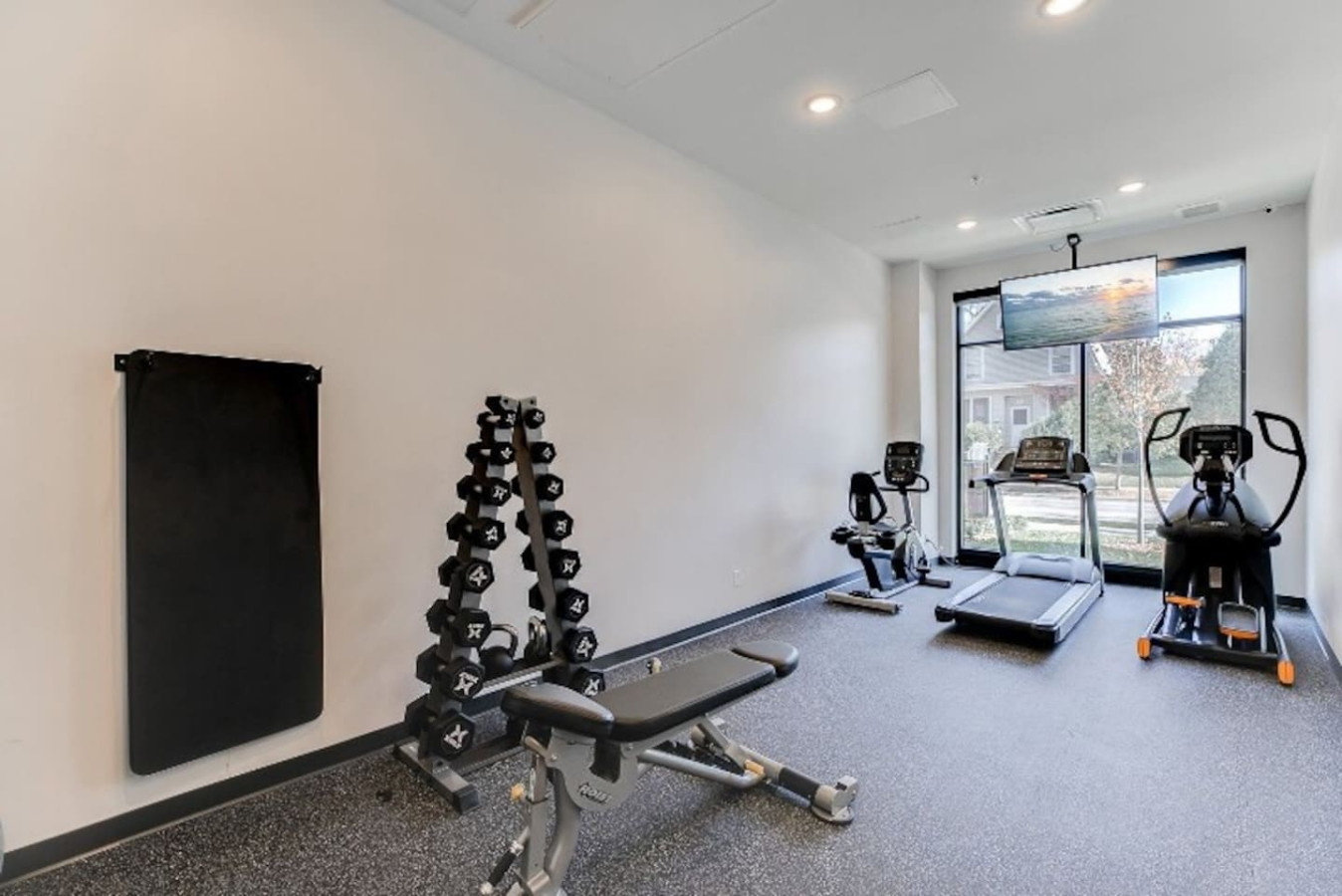 Spacious, well-lit gym equipped with a variety of cardio machines, free weights, and strength-training equipment.
