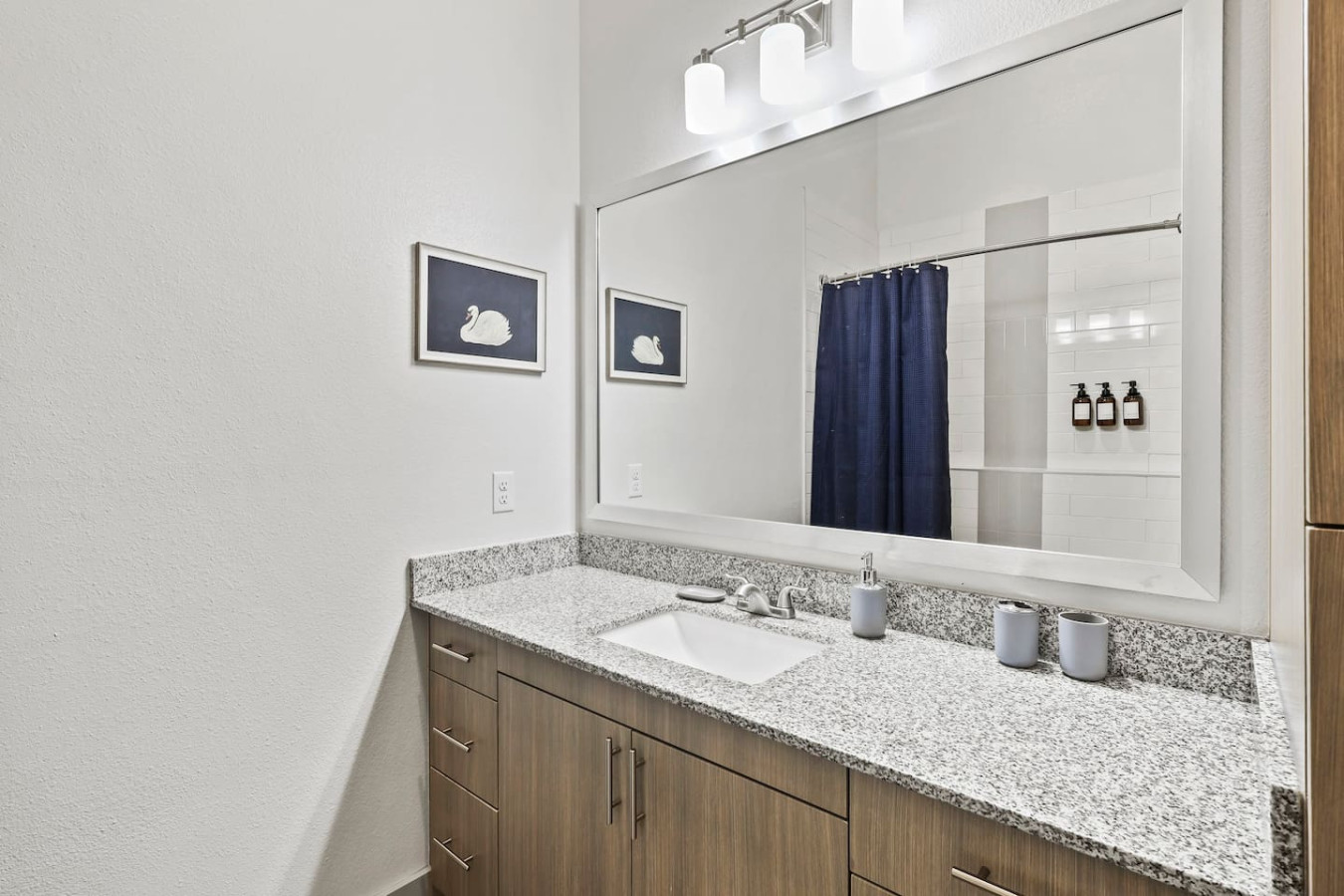 This bright and welcoming bathroom invites you to freshen up in comfort. Enjoy the forest-inspired shower curtain that adds a calming touch to your routine, complemented by the cozy rug underfoot and sparkling clean fixtures.