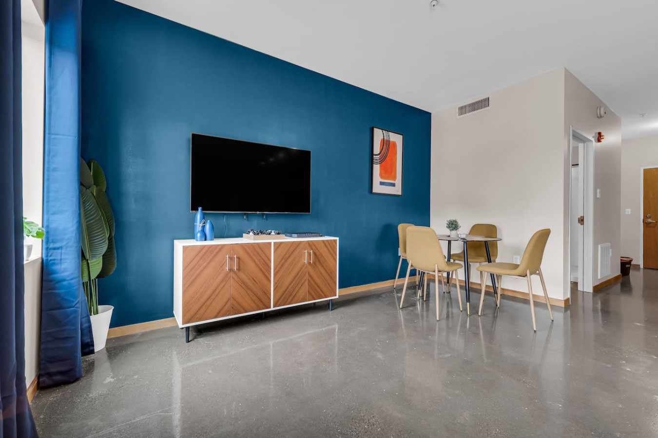 Spacious open-concept living and dining area featuring a vibrant sofa, modern furnishings, and a stylish entertainment setup—ideal for gatherings and relaxation.