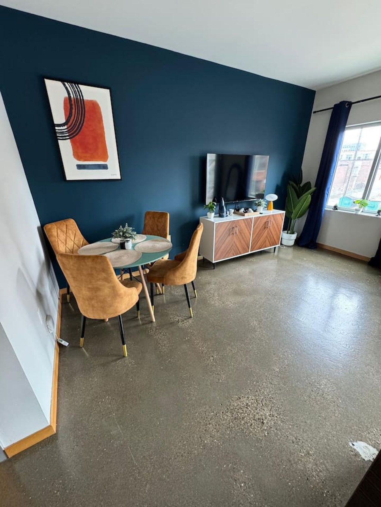 Spacious open-concept living and dining area featuring a vibrant sofa, modern furnishings, and a stylish entertainment setup—ideal for gatherings and relaxation.