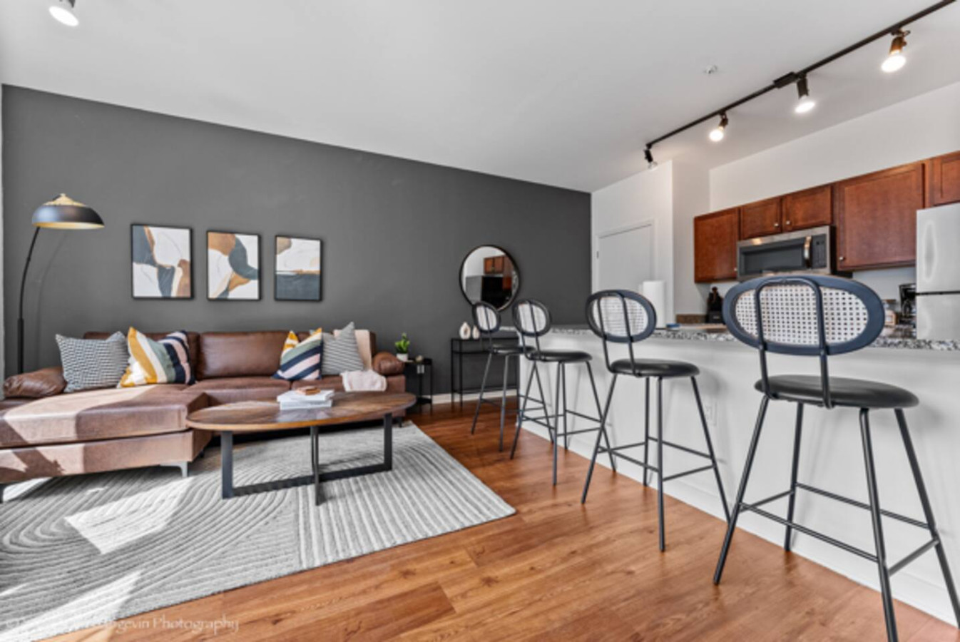 Enjoy a blend of modern comfort and style in this spacious living area. Featuring a plush sofa, chic decor, and a vibrant neon sign, it's perfect for relaxation and socializing. The open layout seamlessly connects to the kitchen and dining area.