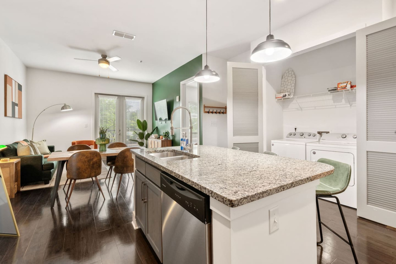 Fully equipped kitchen with stainless appliances, dishwasher, and island seating connects to dining table.