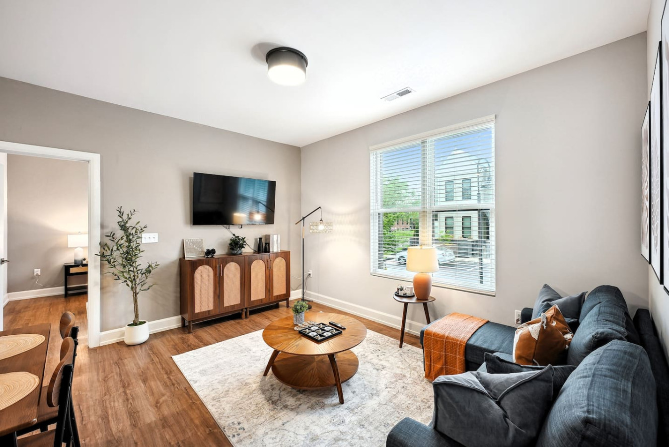 Spacious open-concept living and dining area featuring a vibrant sofa, modern furnishings, and a stylish entertainment setup—ideal for gatherings and relaxation.