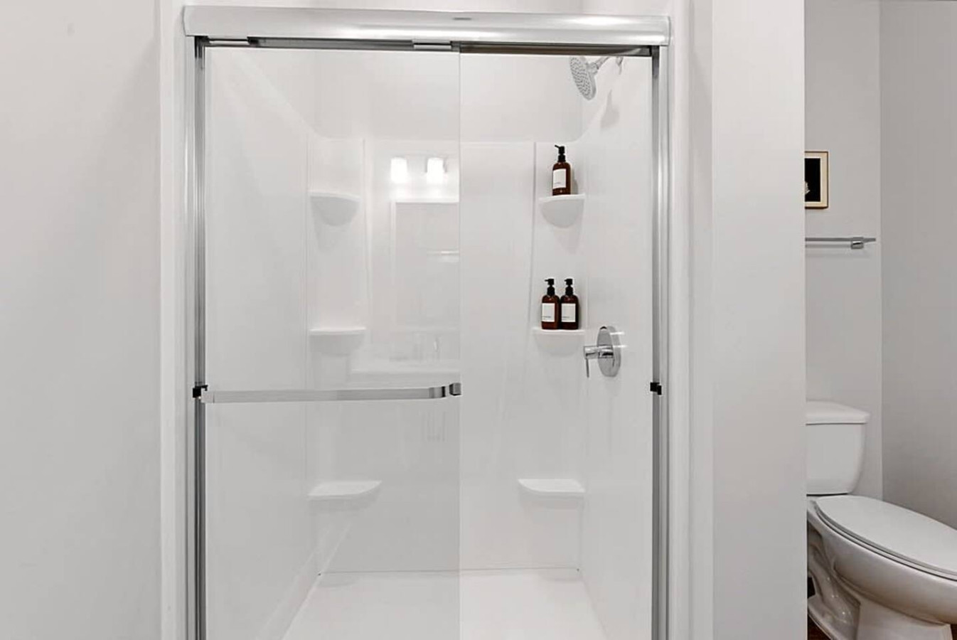 A spotless bathroom featuring a glass enclosed shower, premium bath products, and crisp white finishes. Designed for comfort and simplicity, this space provides a refreshing and calming environment for daily routines.