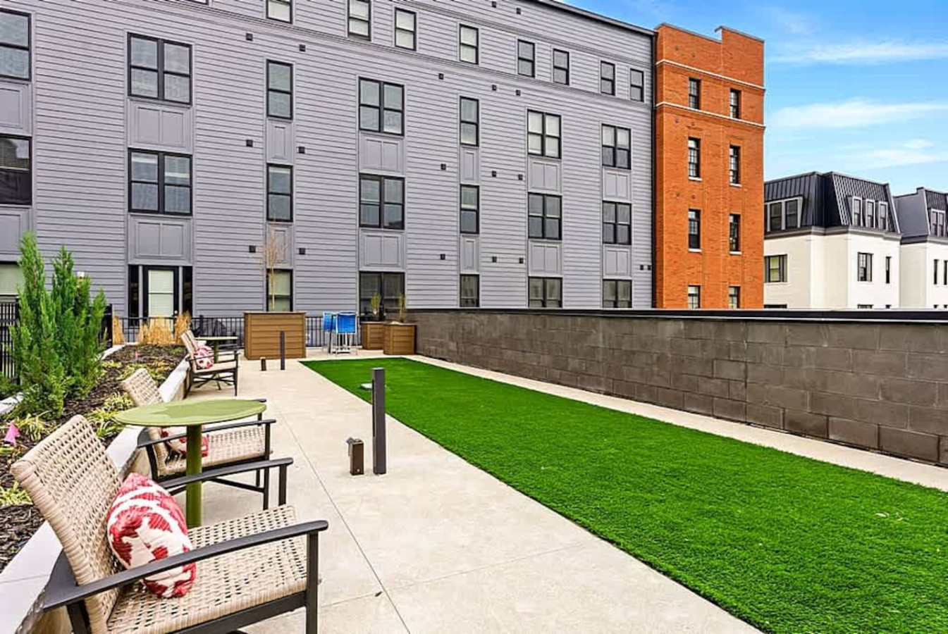 A quiet courtyard with benches, open turf, and clear walkways providing a comfortable outdoor spot for reading, relaxing, or enjoying the community atmosphere. A great place to unwind during your stay.
