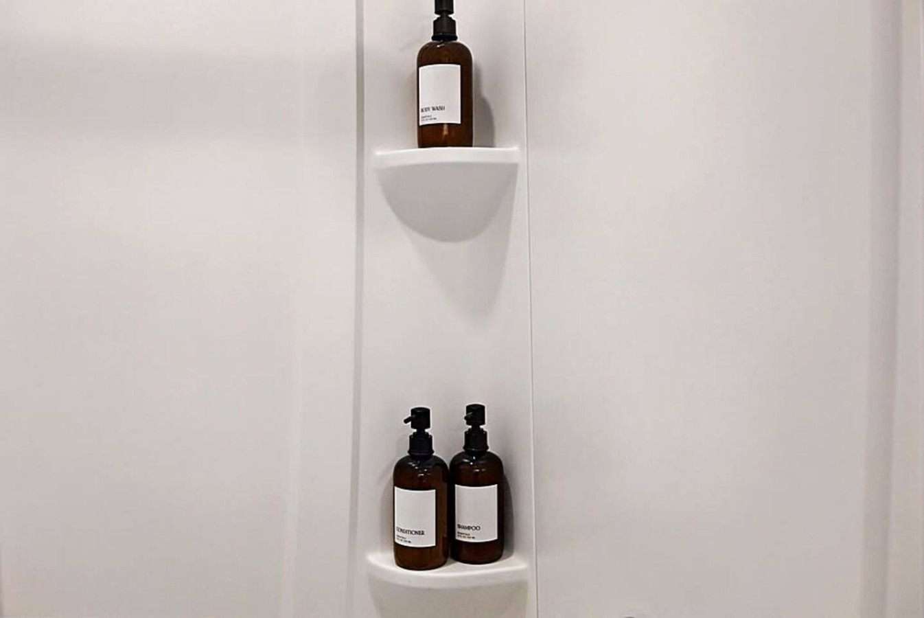 A spotless and modern bathroom offering premium bath essentials and a refreshing walk-in shower. Clean lines and minimalist shelving create a spa-like atmosphere that adds comfort and convenience to your stay.