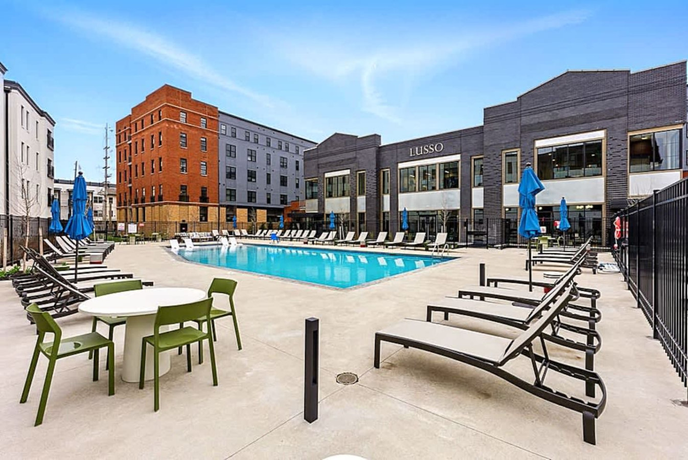 A resort-style outdoor pool surrounded by lounge chairs and modern buildings. Perfect for cooling off, sunbathing, or enjoying a peaceful break during your trip. The area offers a refreshing retreat with plenty of seating.