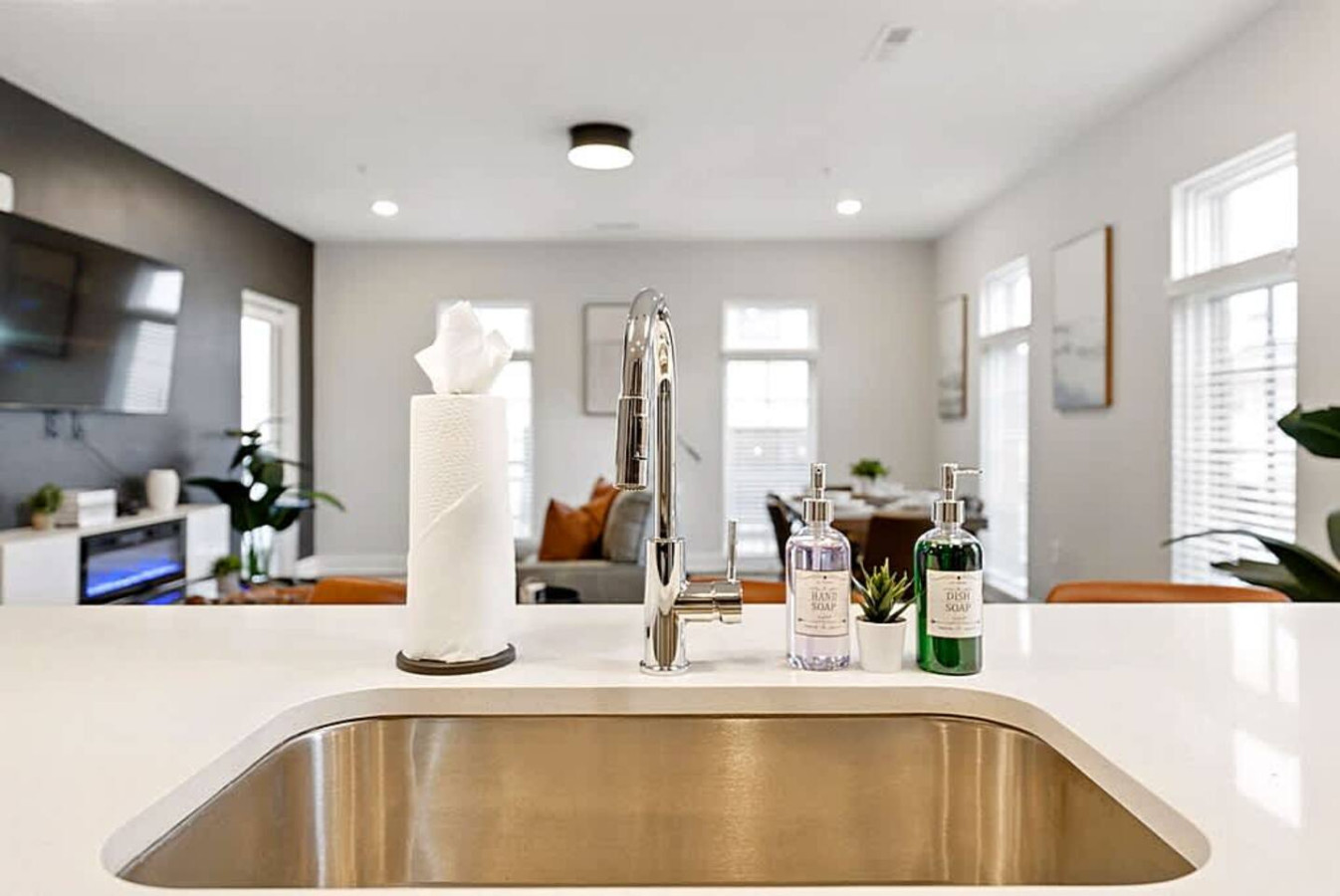 A bright kitchen view from the sink area highlighting the island, seating, and open living space. This layout makes meal prep easy while still allowing you to stay connected with guests in the adjoining rooms.