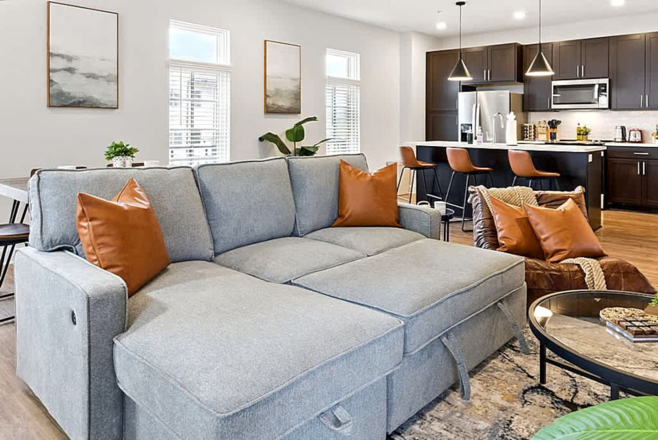 A spacious living area designed for comfort with a sectional sofa, stylish decor, and abundant natural light. This open layout creates the ideal spot to unwind, watch TV, or gather with friends and family after exploring the city.