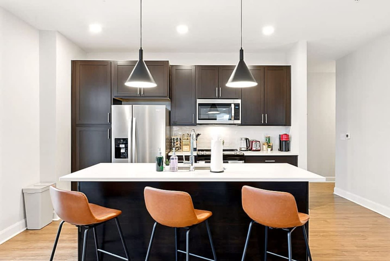 A sleek modern kitchen equipped with stainless steel appliances, ample counter space, and bar seating. Perfect for preparing meals, enjoying morning coffee, or hosting casual gatherings in a warm and functional setting.