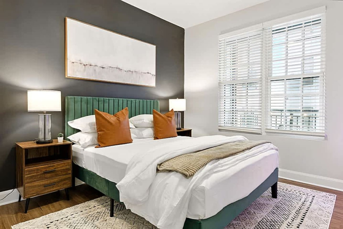 A bright and inviting bedroom featuring a plush bed, soft linens, and warm accent lighting. Large windows fill the space with natural light, creating a calm setting perfect for restful nights and relaxed mornings during your stay.