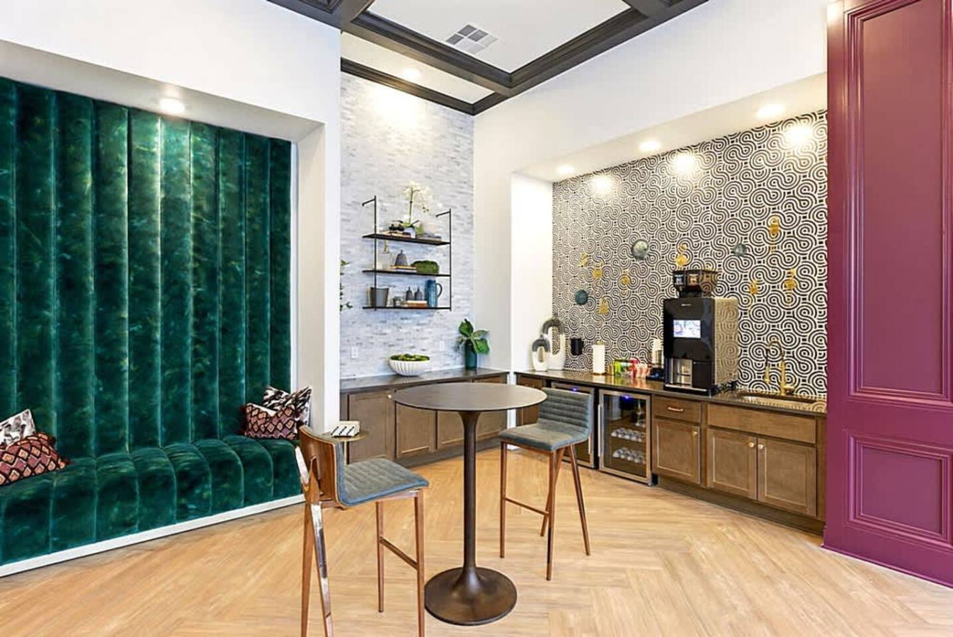 A chic event space featuring a built-in coffee bar, emerald accent wall, and modern seating. A perfect place to enjoy a morning coffee, meet with friends, or relax in a vibrant and thoughtfully designed atmosphere.