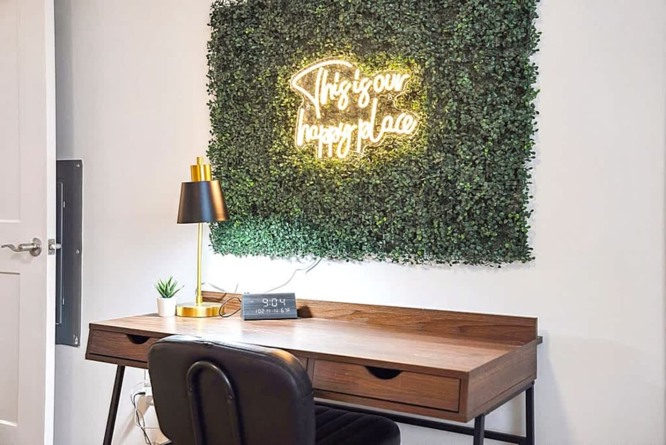 A stylish workspace featuring a modern desk, cozy chair, and decorative greenery wall with soft lighting. Ideal for remote work or studying in a quiet, comfortable environment that feels both inspiring and productive.