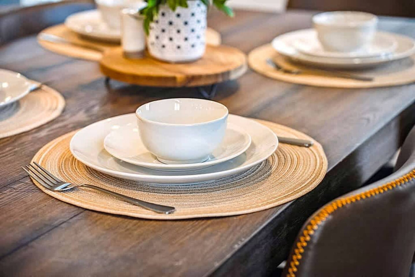 A beautifully set dining table featuring coordinated dishware and woven placemats. This inviting space is perfect for shared meals, celebrations, or enjoying takeout in a warm and stylish environment.