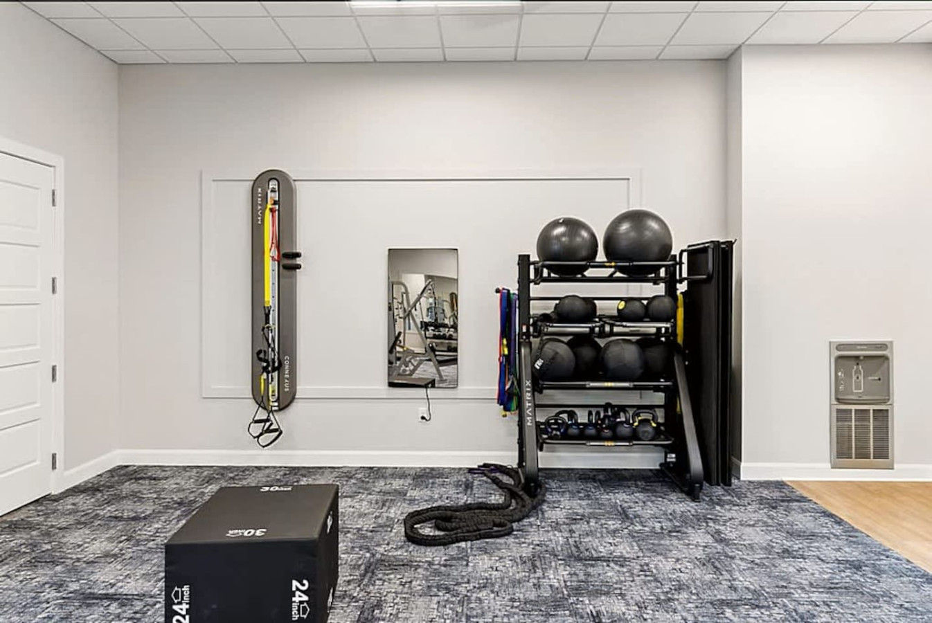A clean and organized gym space featuring resistance gear, wall-mounted training equipment, and open floor area for stretching. Perfect for guests who want a convenient and well equipped workout environment without leaving the building.
