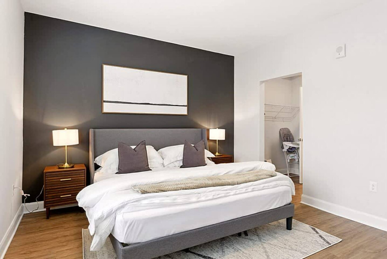 A spacious bedroom with warm lighting, matching nightstands, and a stylish headboard. The clean design and calming tones create an inviting space ideal for relaxation and a great night's sleep.