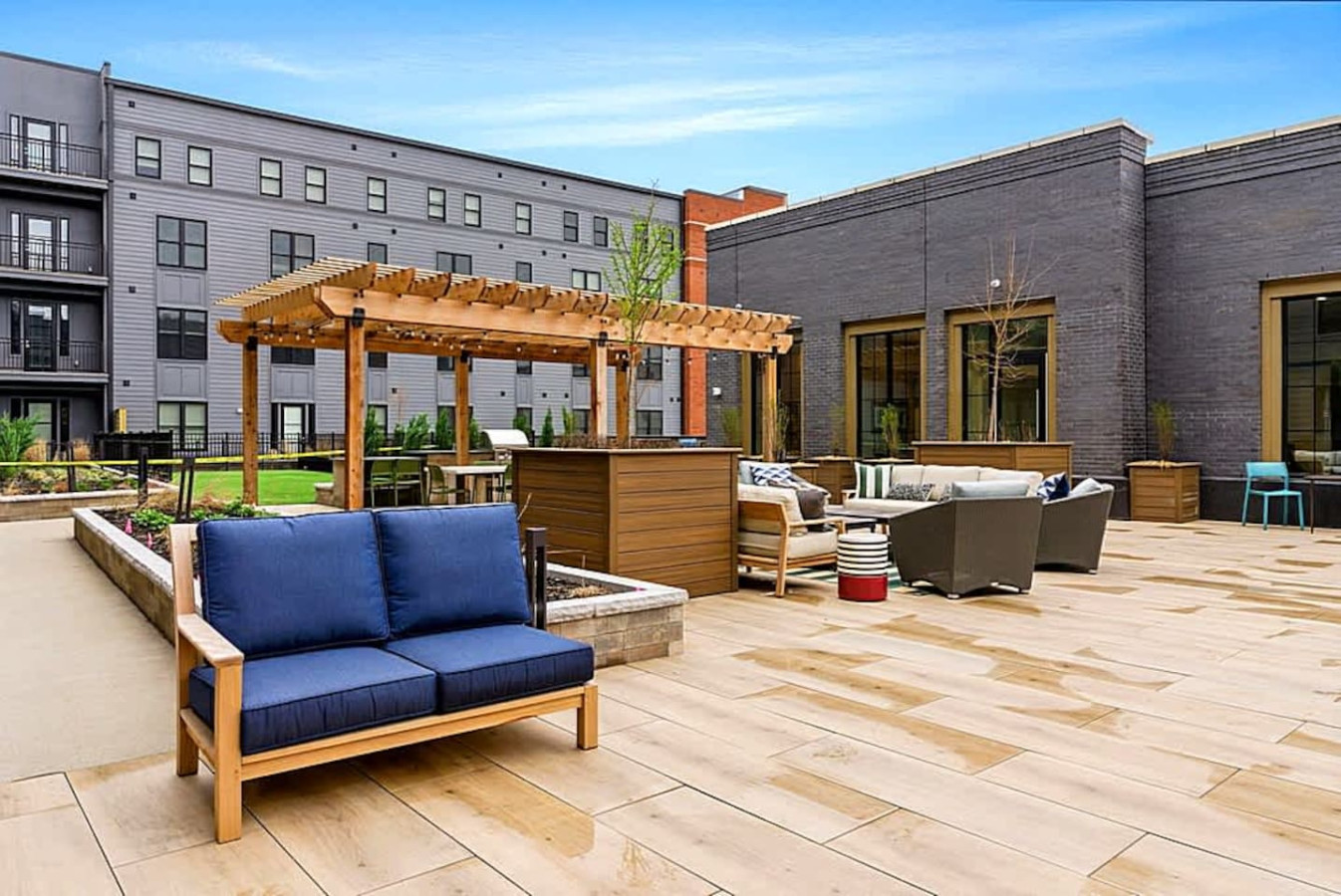 A relaxing patio area featuring cushioned lounge seating and a shaded pergola. This outdoor amenity provides a comfortable spot to unwind, gather with friends, or enjoy quiet afternoons in a beautifully maintained courtyard.