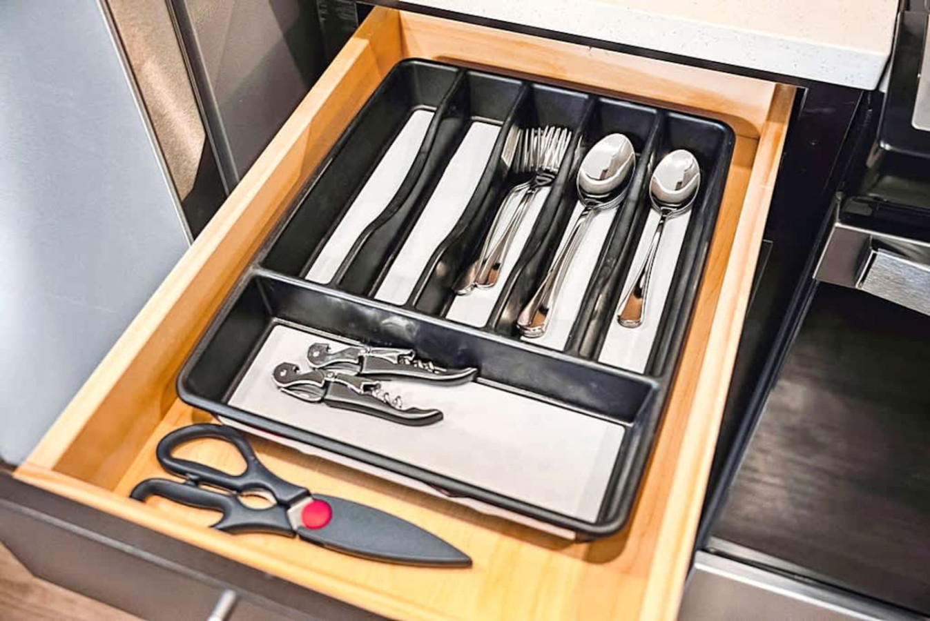 A neatly organized utensil drawer stocked with cutlery and kitchen essentials. This setup ensures guests have everything they need for easy meal preparation and comfortable dining.