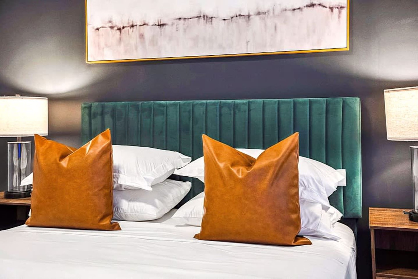 A bright and comfortable primary bedroom with modern bedding, matching lamps, and a bold headboard. The inviting layout creates a peaceful retreat ideal for restful sleep and morning relaxation.