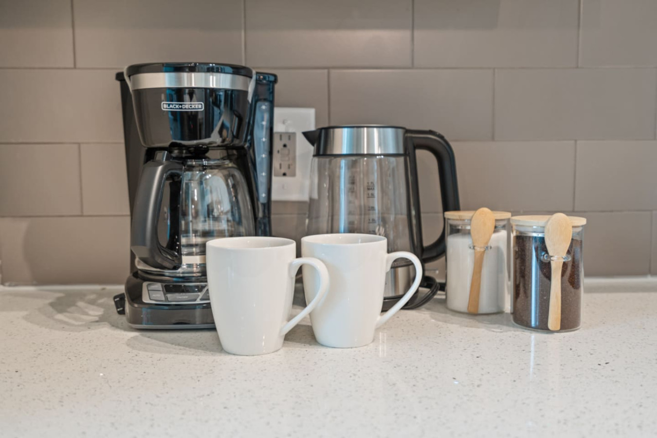 Coffee and tea station ready to go — drip coffee maker, electric kettle, ceramic mugs, and jars of complimentary coffee and sugar. Start your Atlanta morning right without leaving the loft.