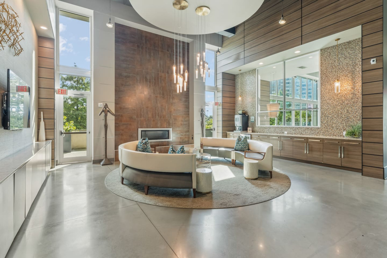 Stunning lobby lounge with a dramatic double-height fireplace, cascading pendant chandelier, and curved designer seating. Mosaic tile accents and polished concrete floors set a boutique-hotel tone from the moment you arrive.