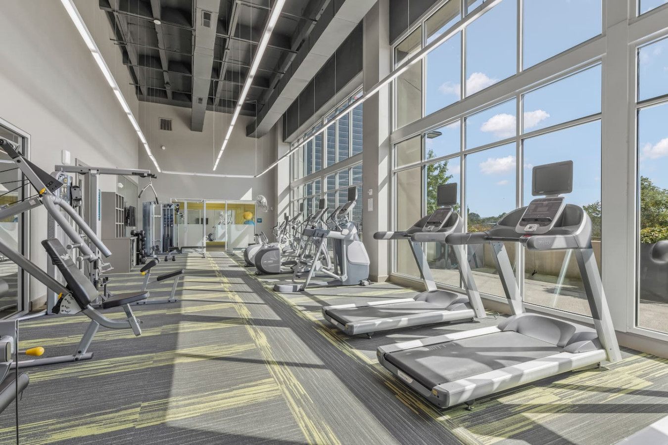 On-site fitness center with floor-to-ceiling windows, treadmills, ellipticals, and strength training machines. Stay on top of your workout routine without leaving the building — complimentary for all guests.