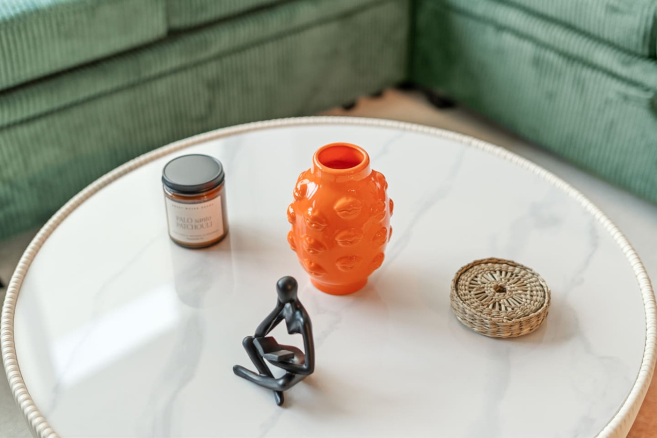 Thoughtful details on the marble-top coffee table — a sculptural orange vase, artisan candle, woven coaster, and modern figurine. Every corner of this loft is styled with personality and warmth.