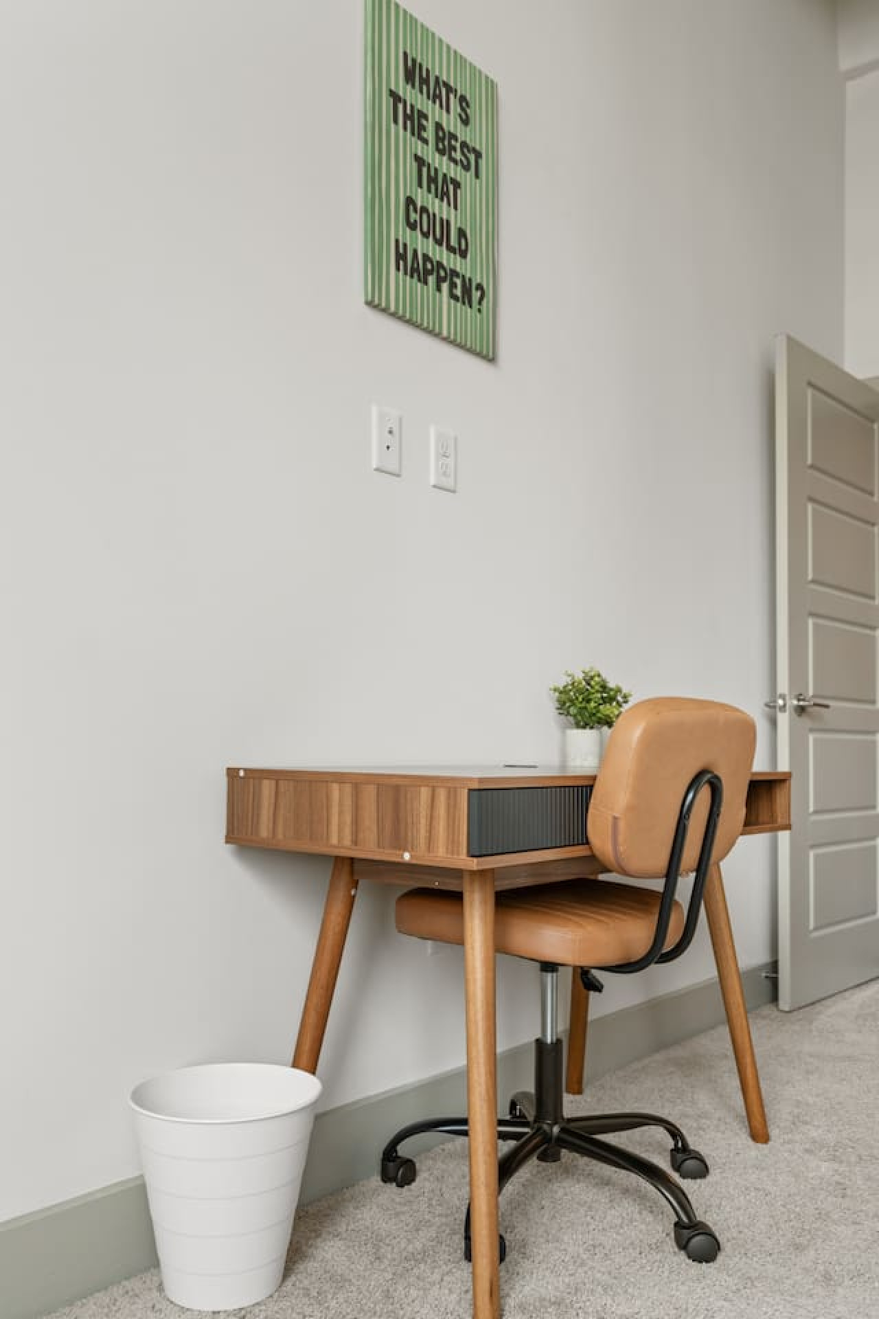 Dedicated workspace in the bedroom with a mid-century walnut desk, cushioned rolling chair, and convenient power outlets. Ideal for remote work or catching up on emails during your Atlanta stay.
