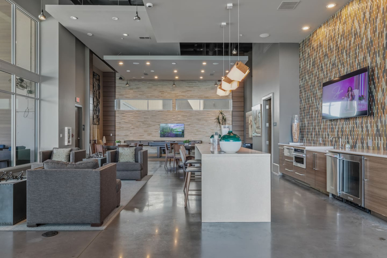 Clubhouse lounge with a full demonstration kitchen, wine cooler, plush seating areas, and multiple TVs. An upscale common space for socializing, working remotely, or hosting a gathering during your stay.