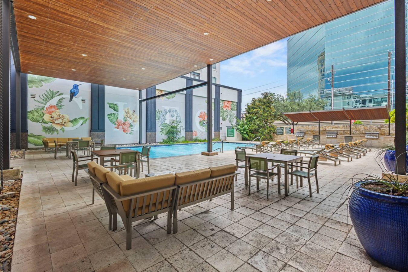 Resort-style pool deck with lounge seating, dining tables, and shaded areas, perfect for relaxing or entertaining guests.