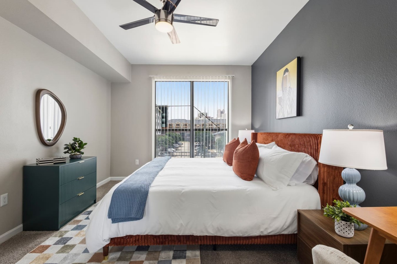 Spacious bedroom with king bed, ceiling fan, and city view.