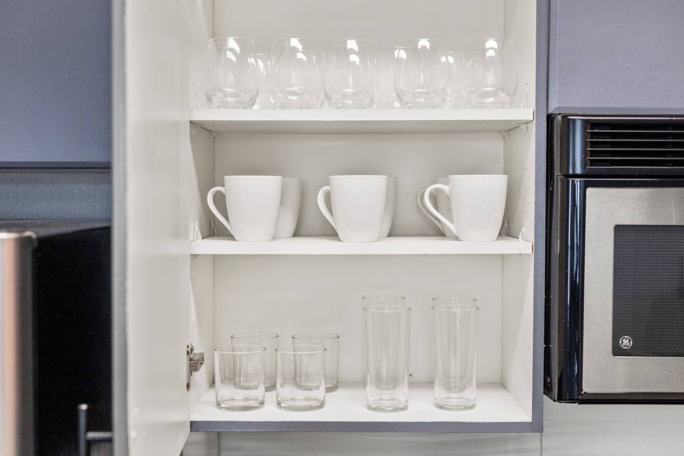 Cabinet stocked with mugs and glasses for drinks.